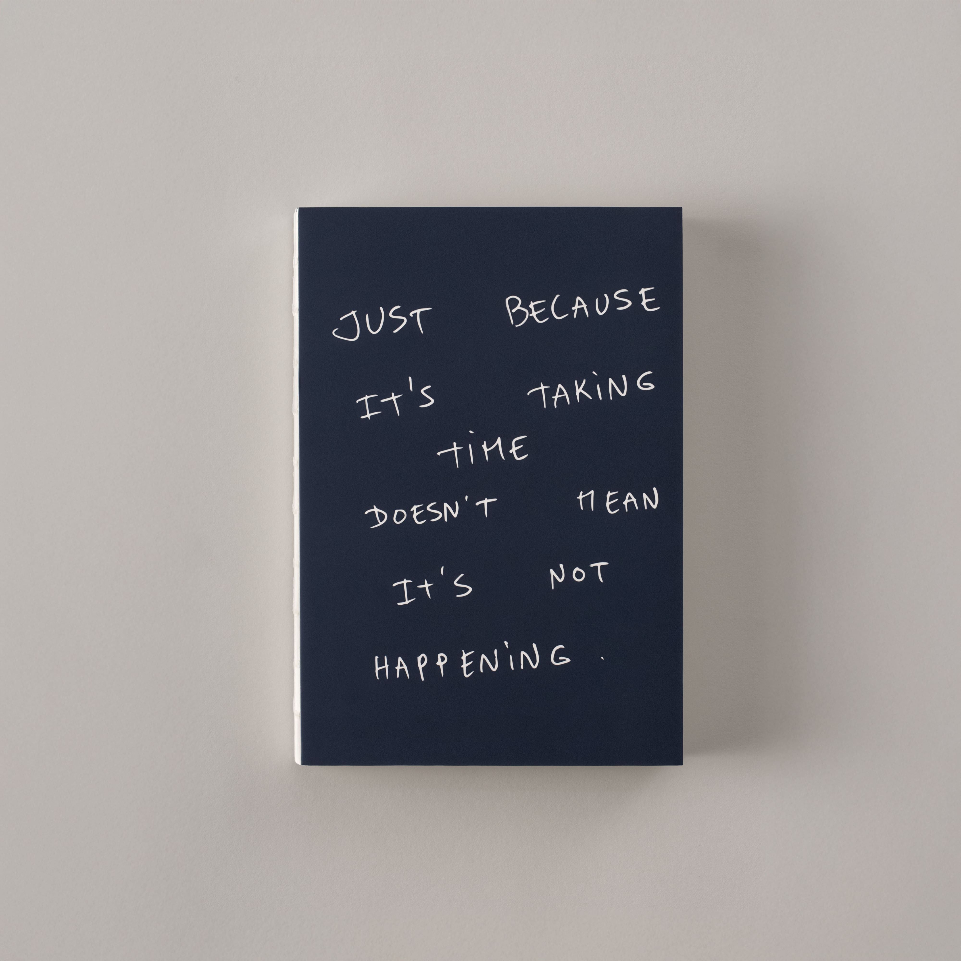 Gray notebook with text: 'I want a coffee, a tattoo, and a vacation.'